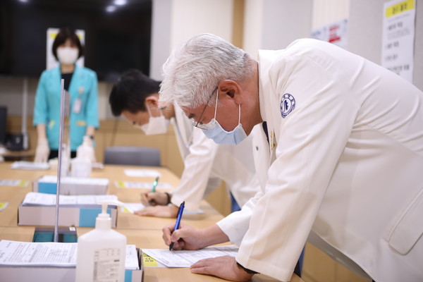 인하대병원 김영모 병원장(사진 앞)과 이진수 감염관리실장(사진 뒤)이 화이자 백신 접종에 앞서 예진표를 작성하고 있다.