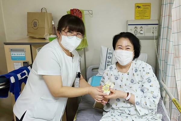 안양윌스기념병원 6병동 우은경 수간호사(사진 왼쪽)가 ‘가래떡 데이’를 맞아 환자에게 가래떡을 나눠주고 있다.