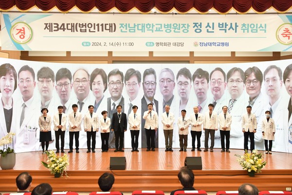 전남대학교병원 정신 신임 병원장(왼쪽에서 여덟 번째)이 2월 14일 오전 11시 명학회관 대강당에서 열린 제34대 병원장 취임식에서 보직을 맡은 교수들과 함께 단상에 올라 인사하고 있다.